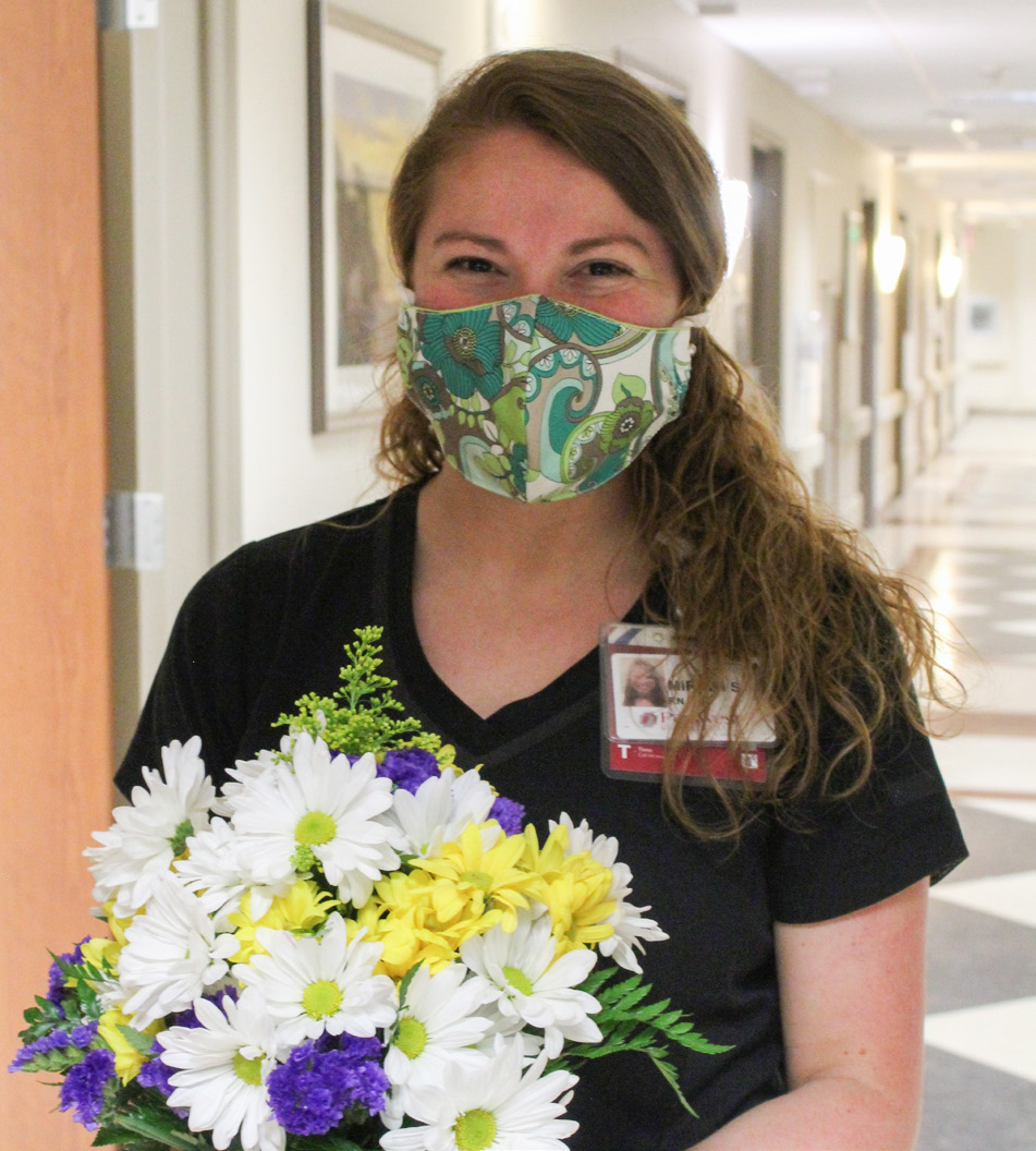 Miriam Smith holding daisy floral arrangement.