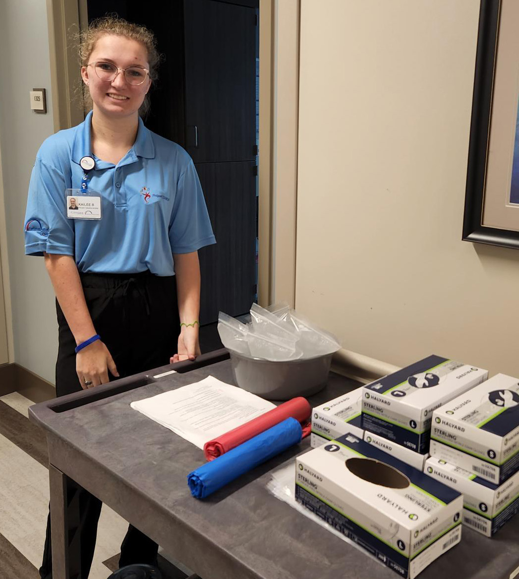 Kailee pictured with cart full of supplies in hallway.