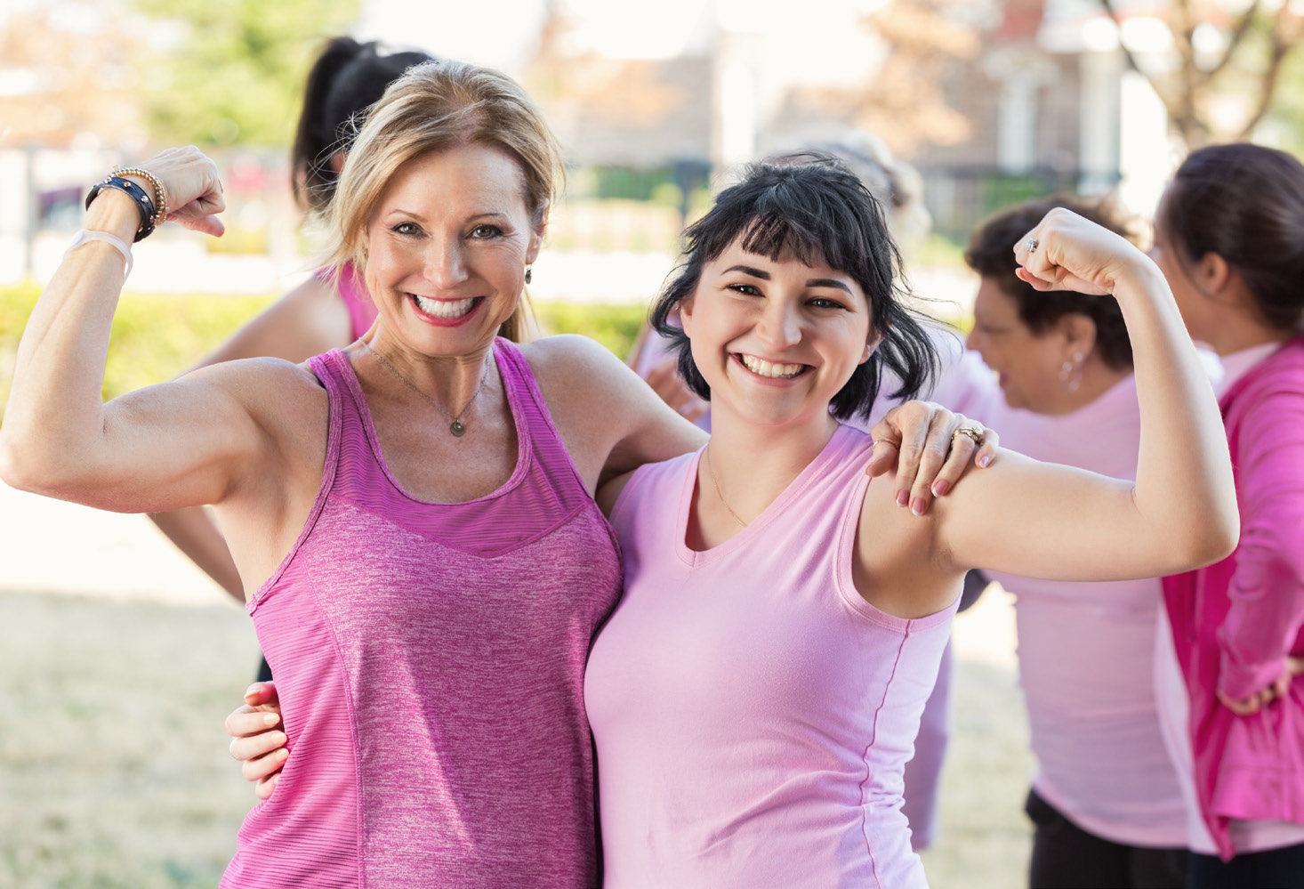 Two women in pink workout attire, showing their muscles.