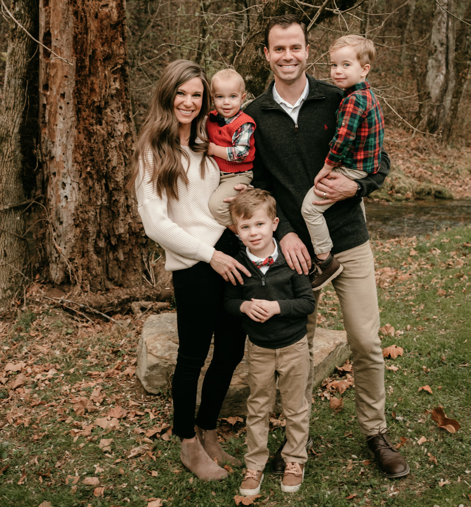 Jamie Turner dressed in fall outfit, posing with her husband and three chidren.