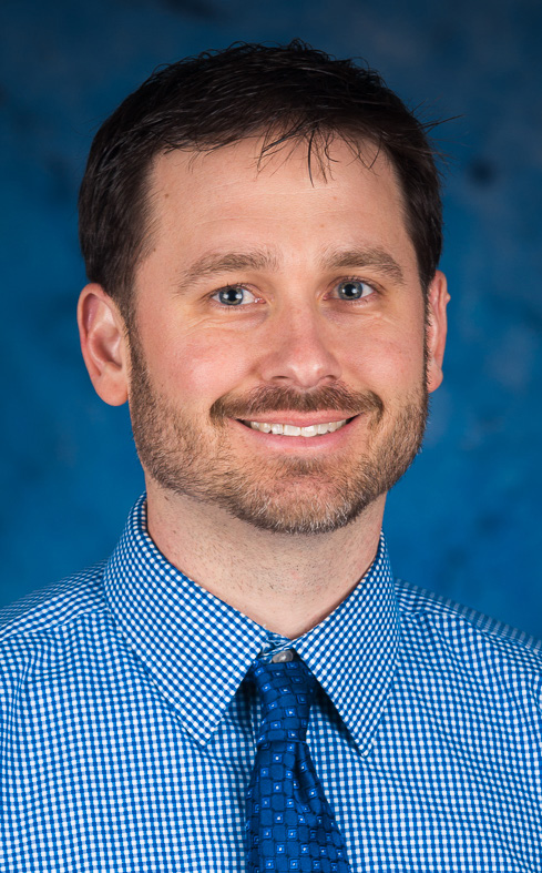 Headshot of Ryan Tipton in blue dress shirt with blue tie.