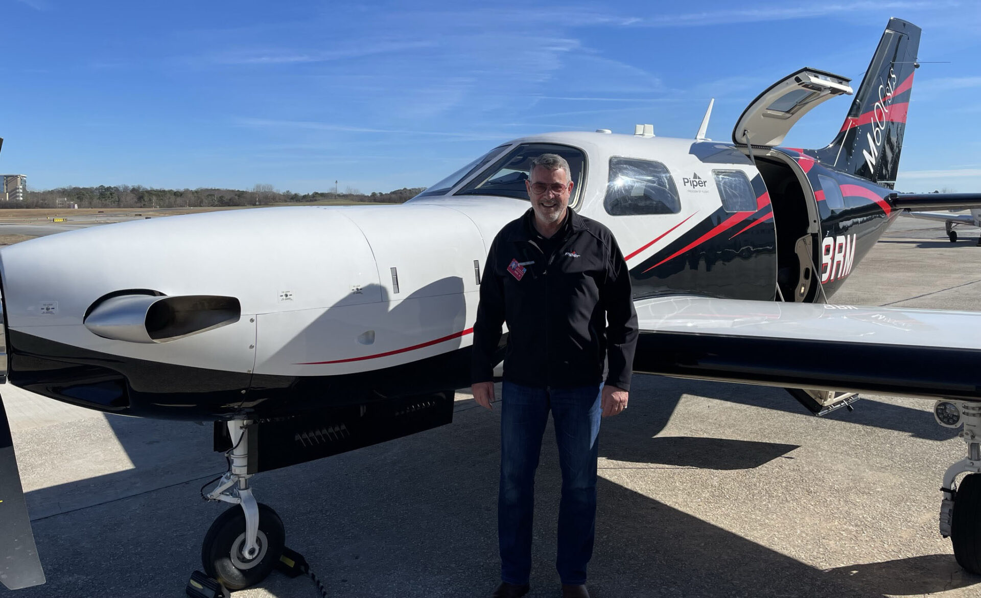 Ross Matthews standing in front of small personal airplane.