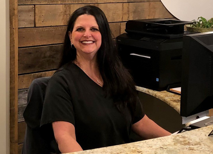 Christy Garland sitting behind her desk at work, wearing a black shirt.