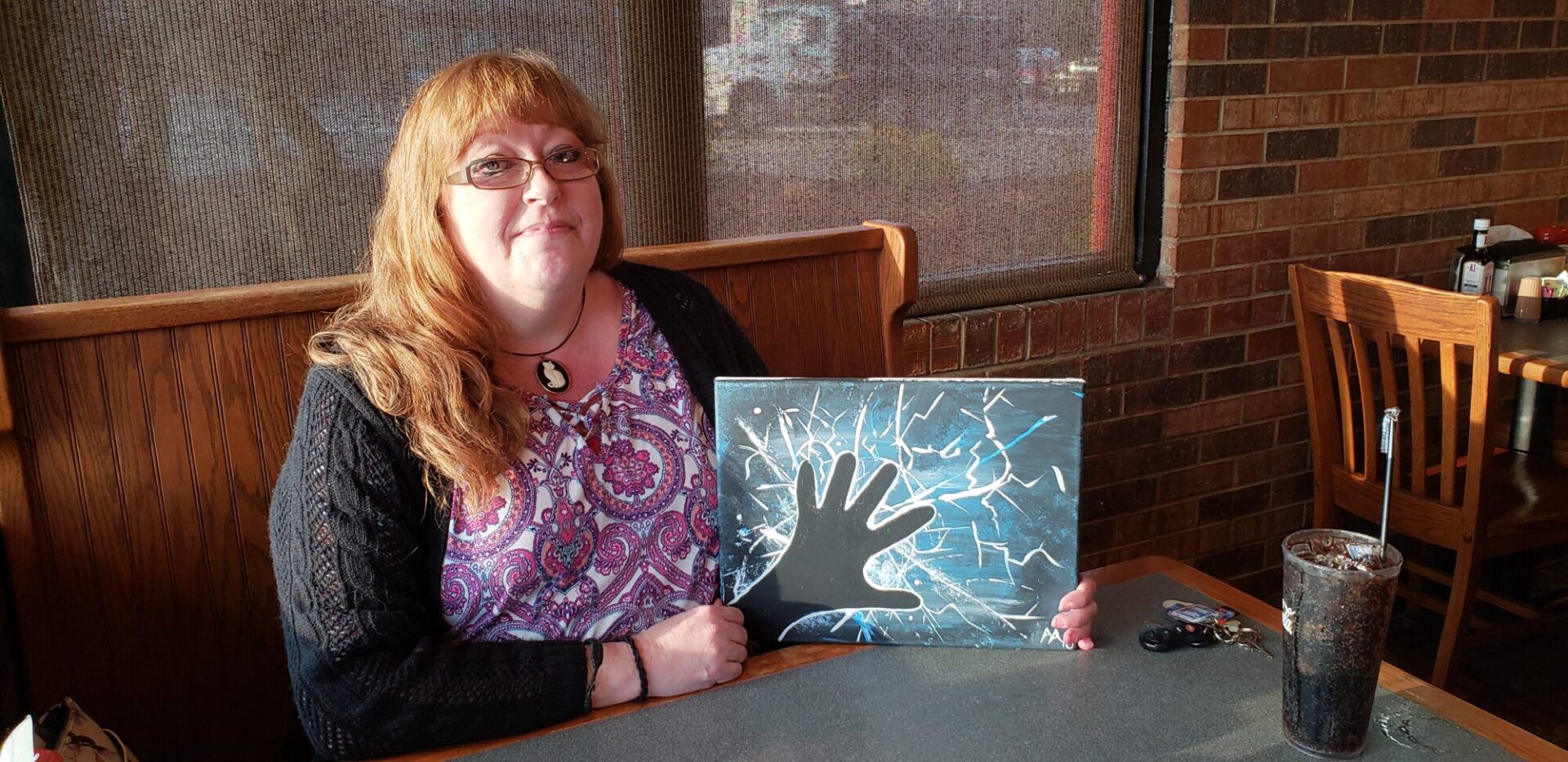 Peninsula patient Andee Anderson shows her first painting of a hand reaching out of the darkness. 