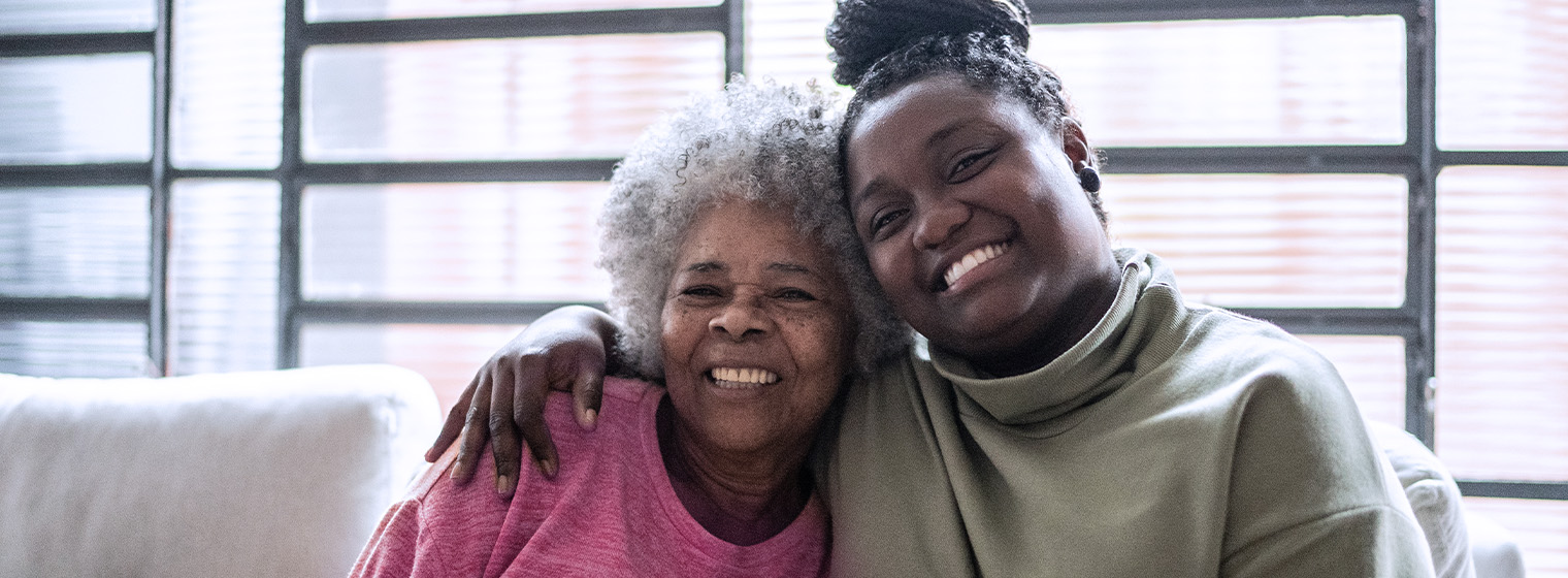 elderly mom and her adult daughter smiling together