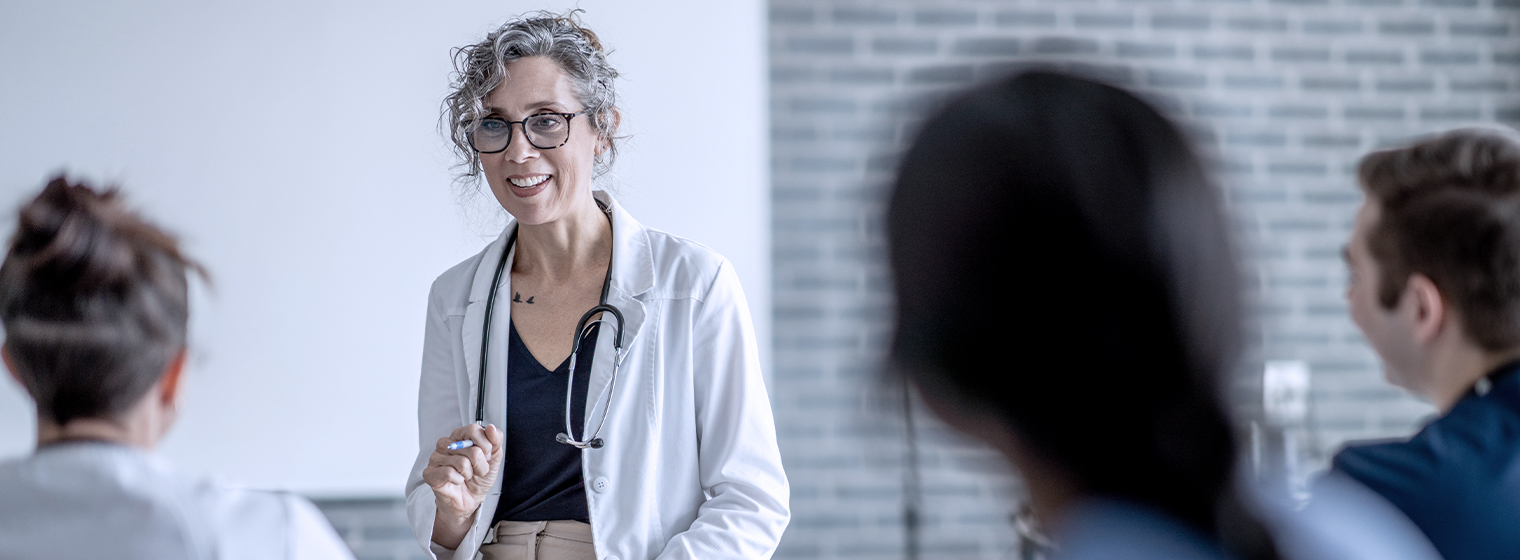 female doctor in scrubs speaking to a group of three people