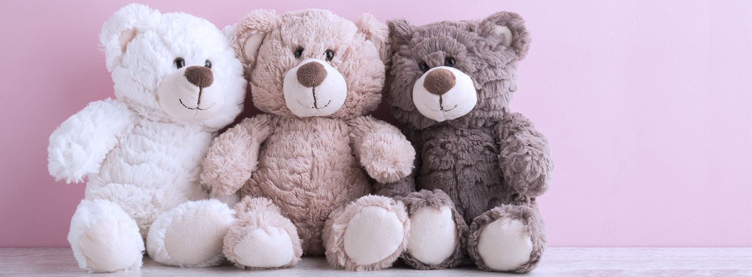three teddy bears on pink background
