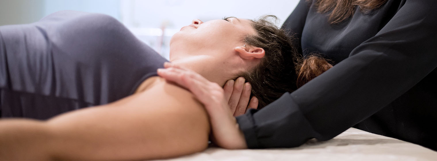 physical therapist massages female patient's neck and shoulders