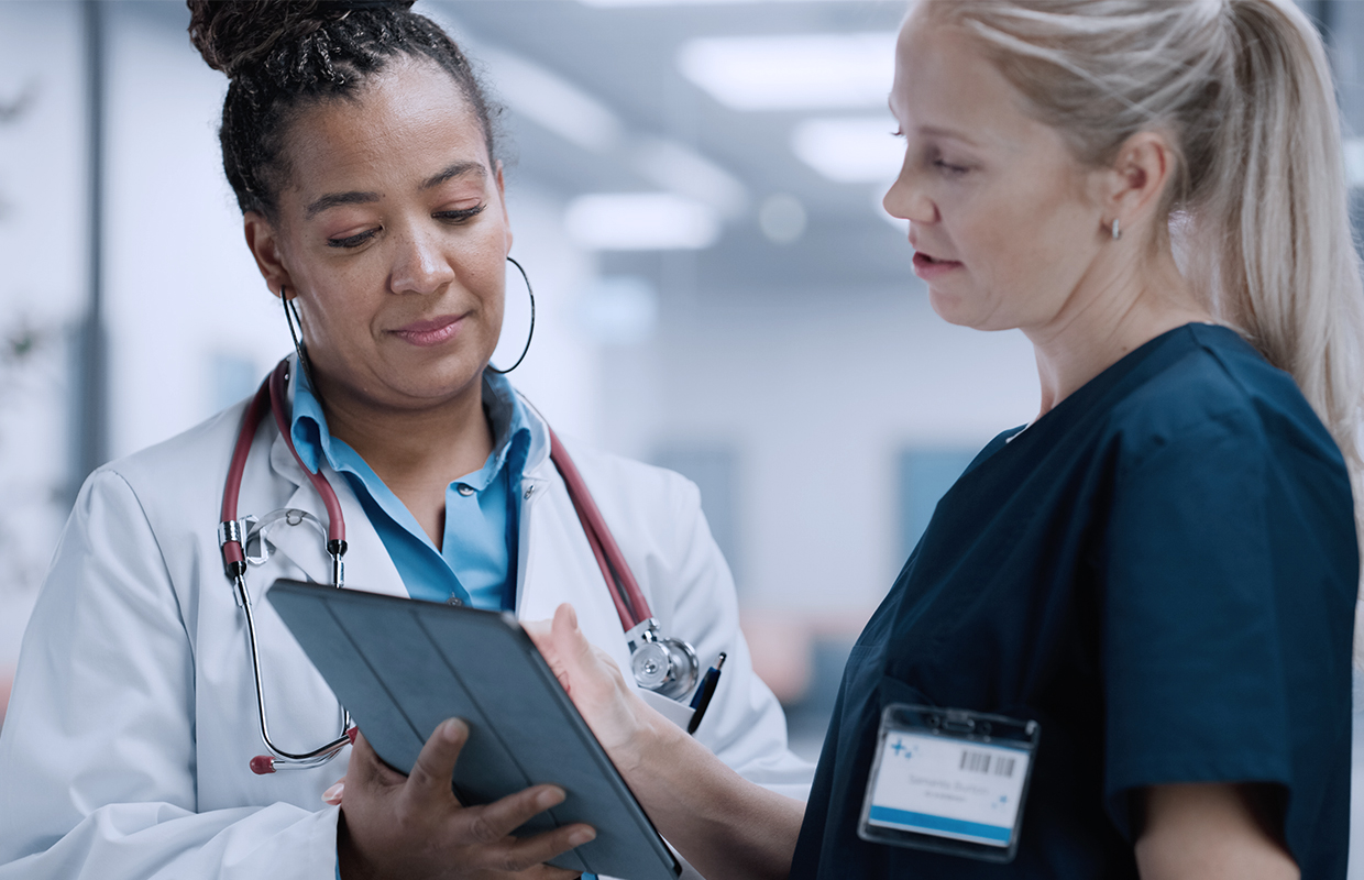 female doctor helping young female nurse on ipad