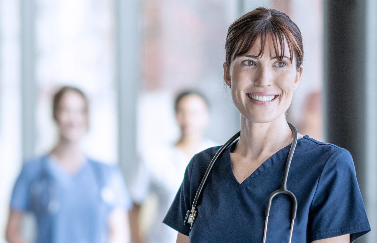 young female student nurse smiling with other students blurred in background