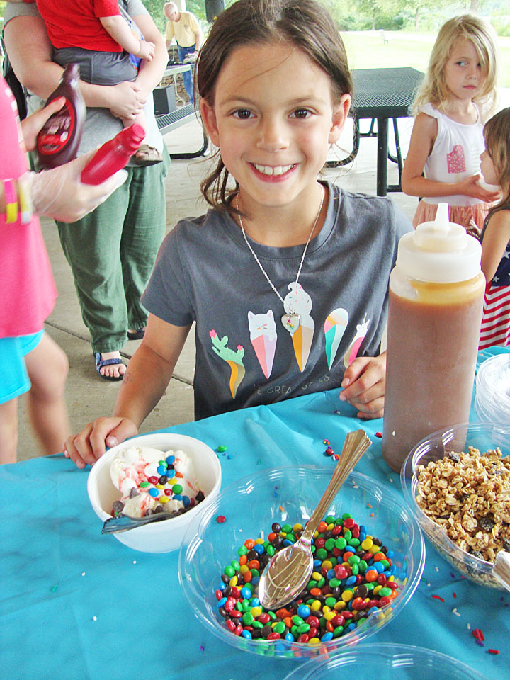 Young girl smiling in front of her homemade ice cream sundae