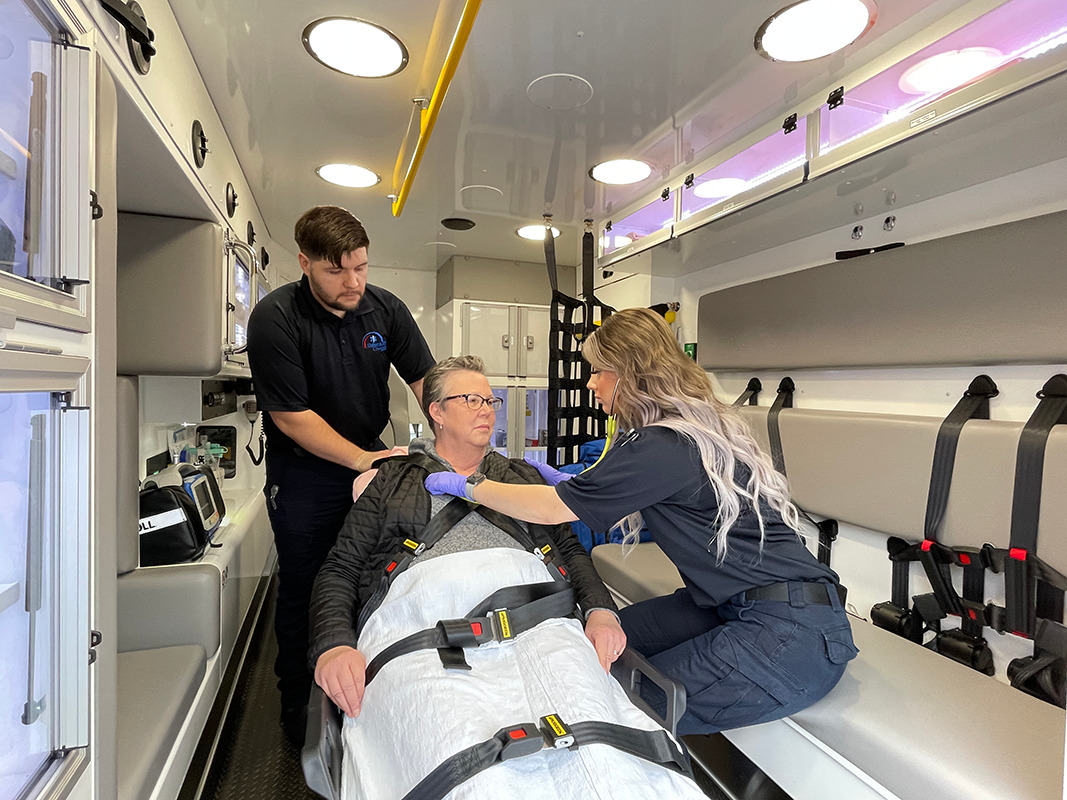 two first responders caring for a female patient in an ambulance