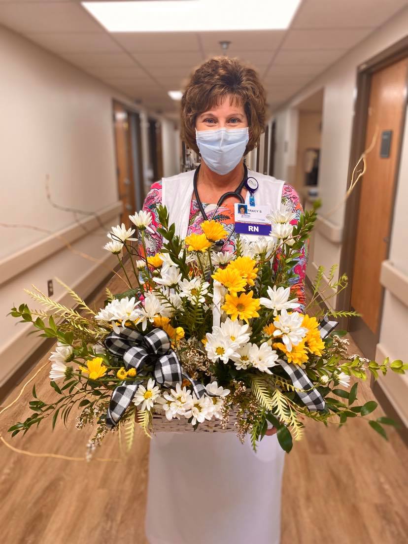 Oncology nurse Tracy Smaron holding her custom-made floral arrangement from her DAISY award presentation.