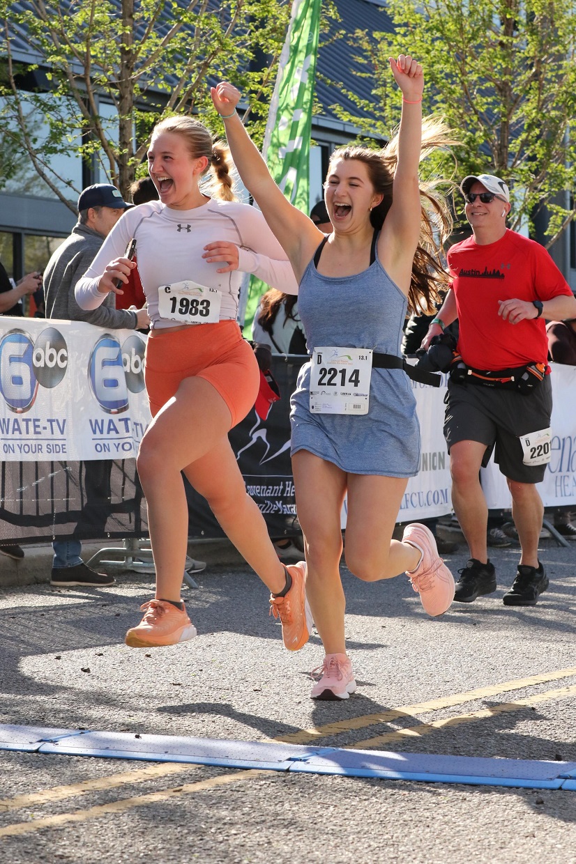 Two women with hands raised as they cross the finish line.