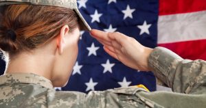 a female soldier salutes an American flag.