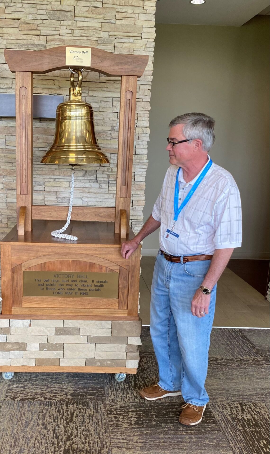 Patient Kevin Murphy poses with Thompson Proton Center's Victory Bell upon completing his cancer treatment at Thompson Proton Center. 