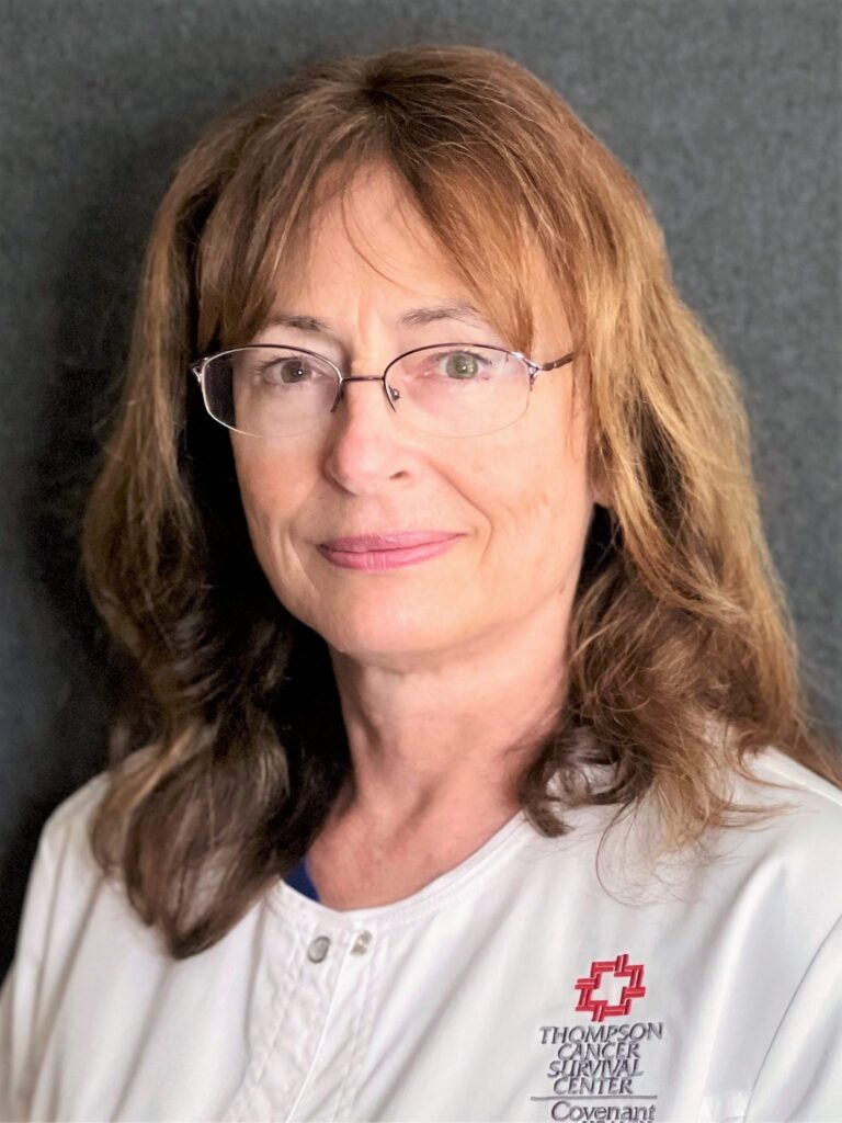 A woman with light brown hair and glasses, wearing a white medical coat with the Thompson Cancer Survival Center Covenant logo, stands in front of a dark background, representing expertise in oral chemotherapy.