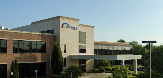 A modern medical building with a Covenant Health sign, large glass windows, and a covered entrance surrounded by greenery under a clear blue sky houses the Thompson Proton Therapy Center.