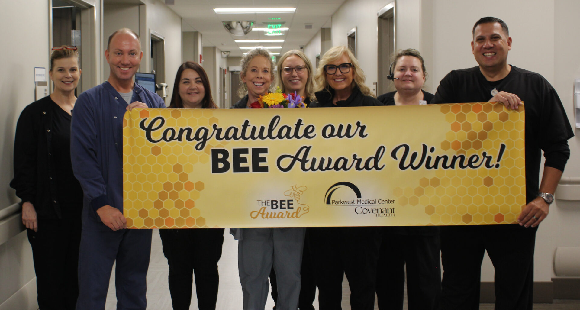 Linda is pictured with leadership team and co-workers holding the BEE banner for group photo.