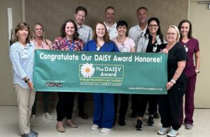Emily is pictured with leadership team and DAISY banner after receiving DAISY Award. 
