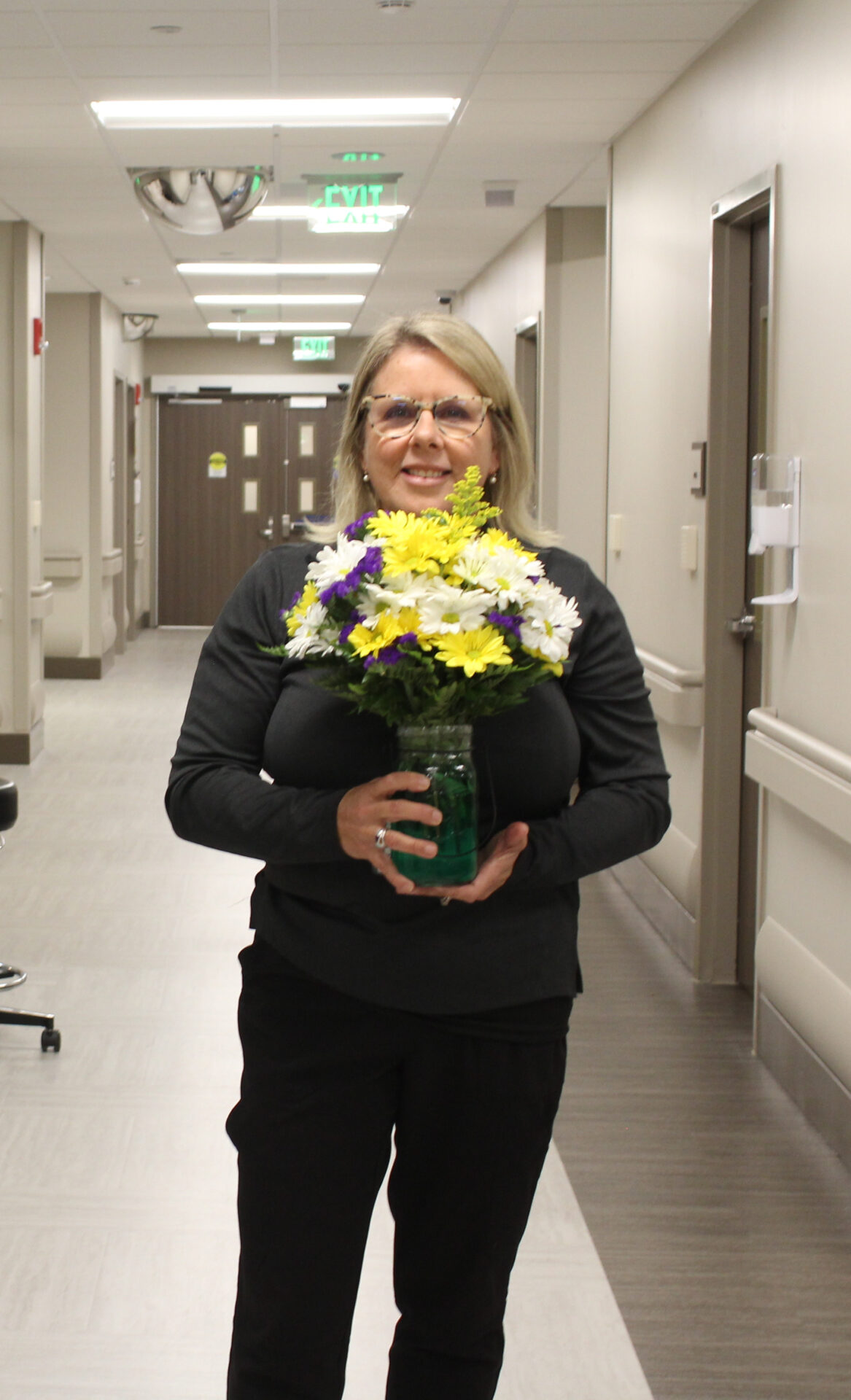 Pamela is pictured holding a DAISY flower arrangement in hallway.