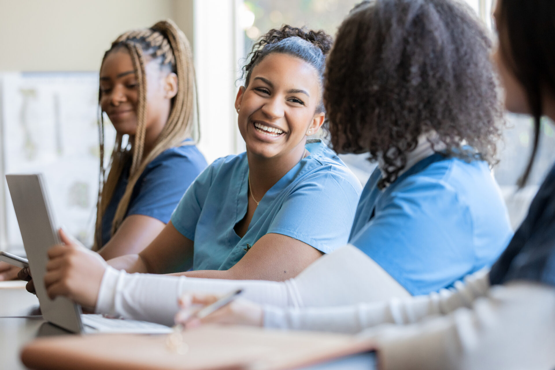 three young adult females in scrubs with one laughing