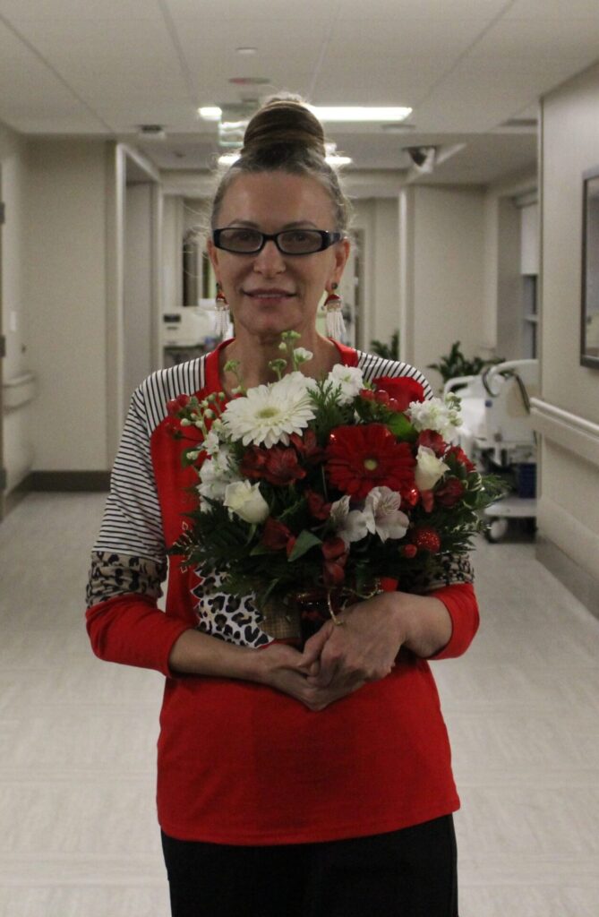 Tatyana smiling, holding arrangement of daisies.