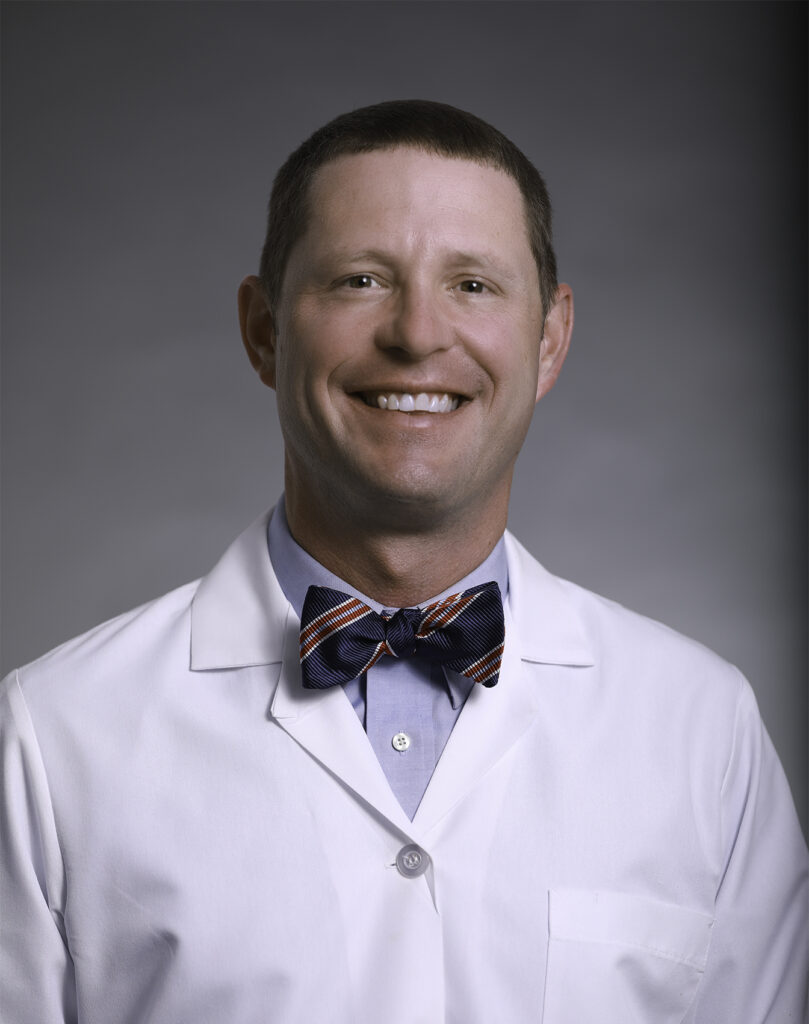 Urologist Michael Douglas wearing his white coat and bowtie, smiling at the camera