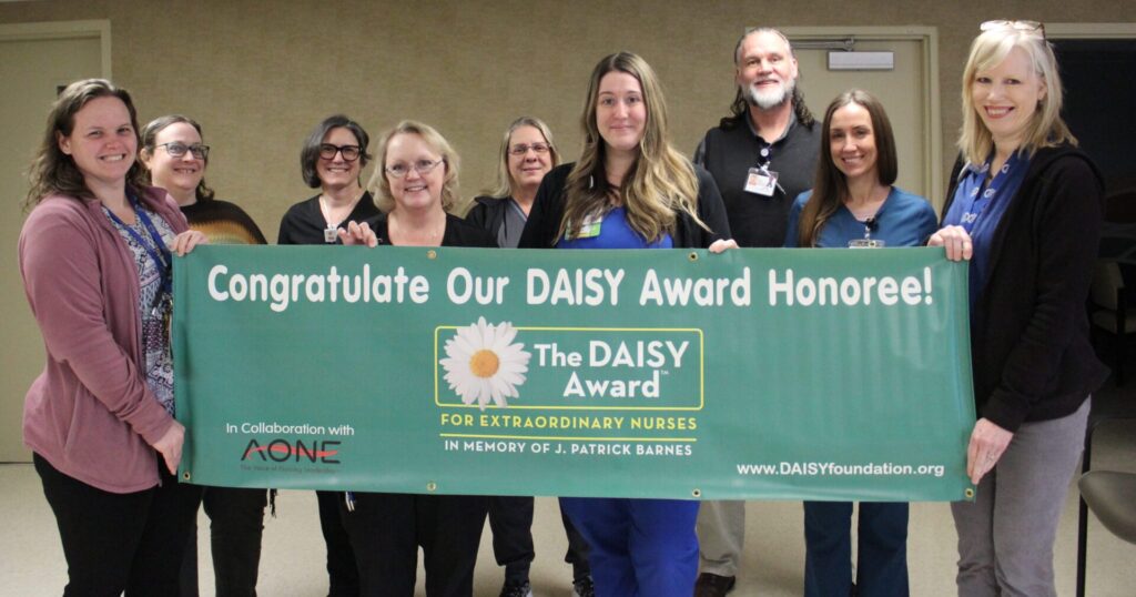 Group of people holding DAISY Award banner.
