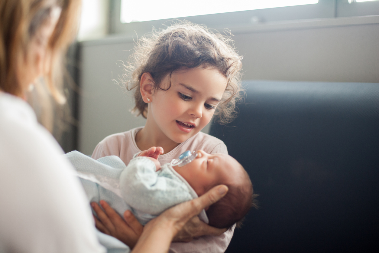 girl holding newborn baby