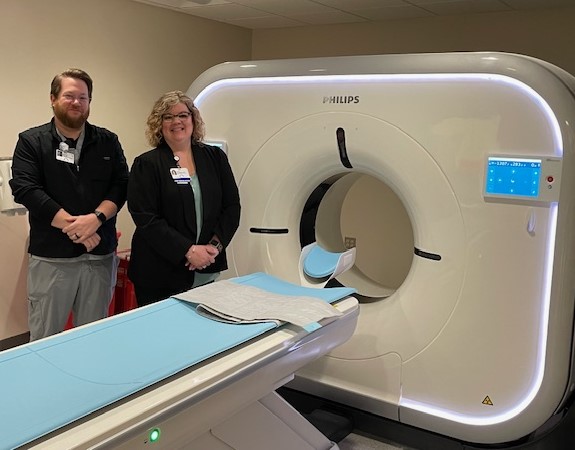 Man and woman staff members standing by CT scanner