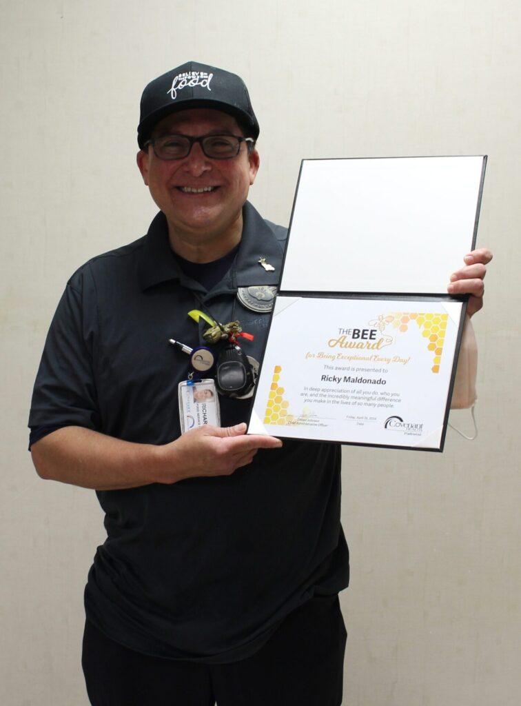 Ricky pictured by himself holding his BEE certificate with a smile.