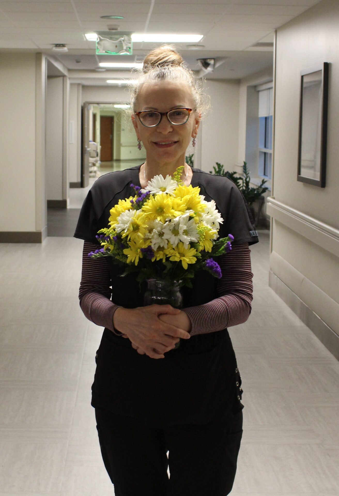 Tatyana pictured in a long hallway holding her beautiful DAISY flower arrangement.