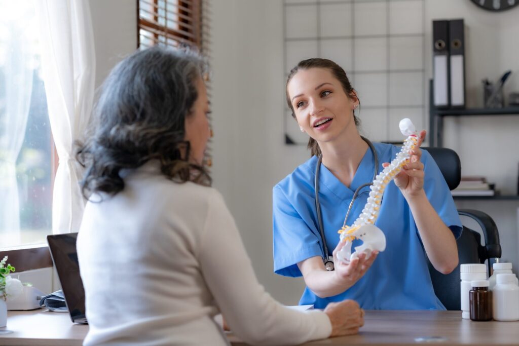 Nurse uses spine model to explain bone-thinning and osteoporosis to patient 