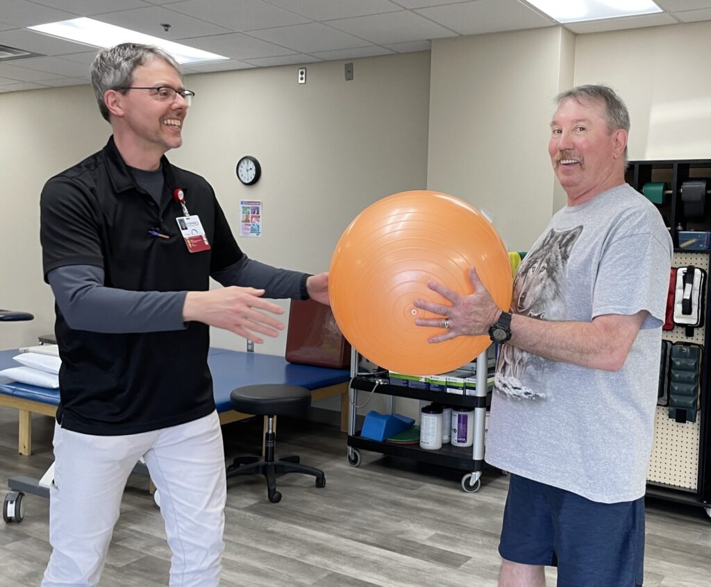 Male-occupational-therapist-tossing-large-ball-to-patient-recovering-from-stroke