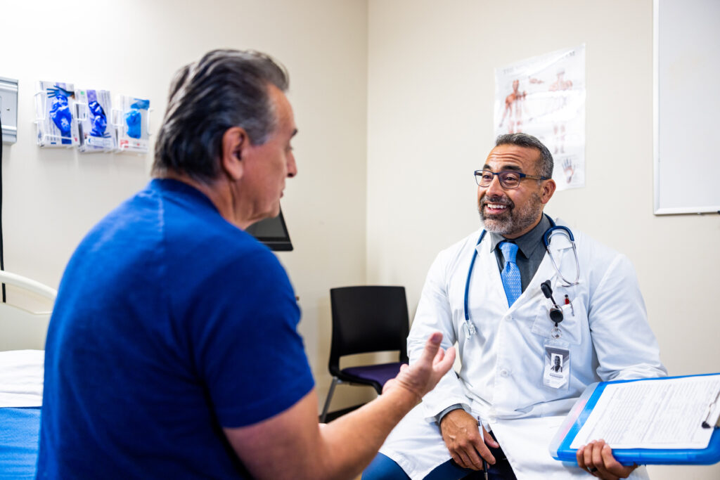 Seated older man talks with male primary care physician about men's health issues.