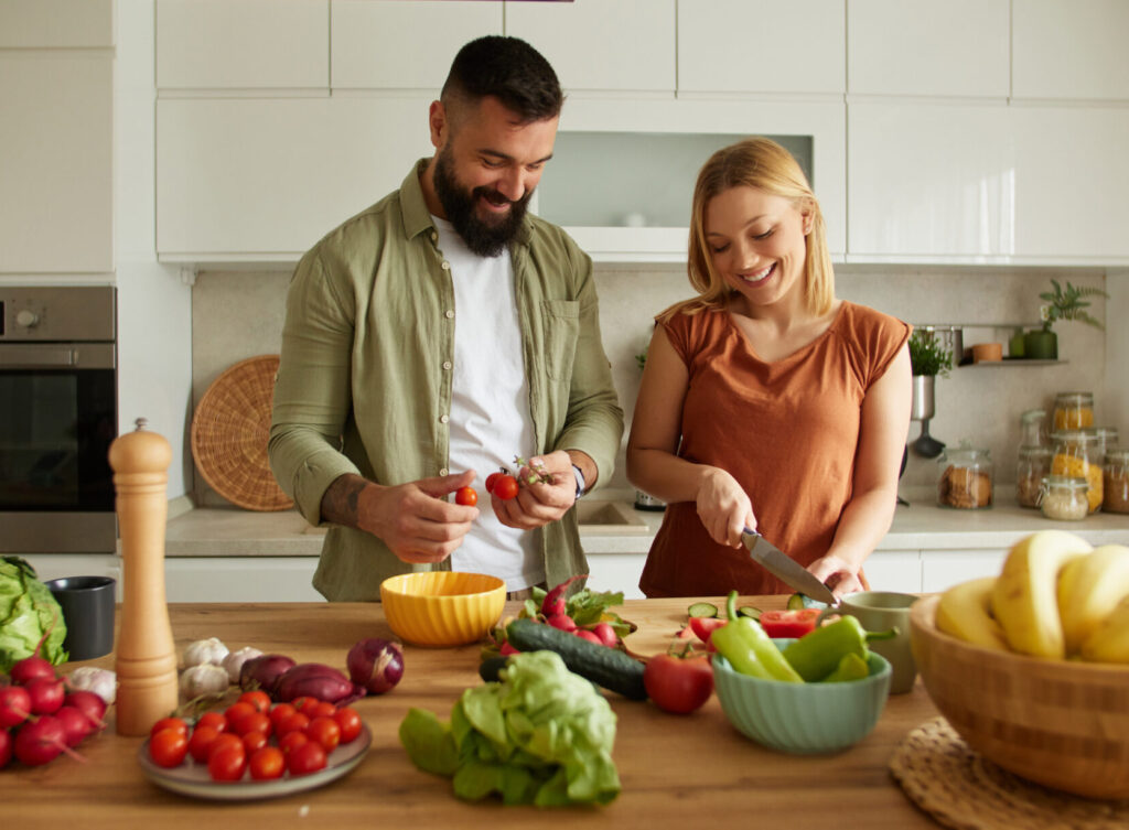 man and woman preparing healthy fruits and vegetables to support the gut microbiome