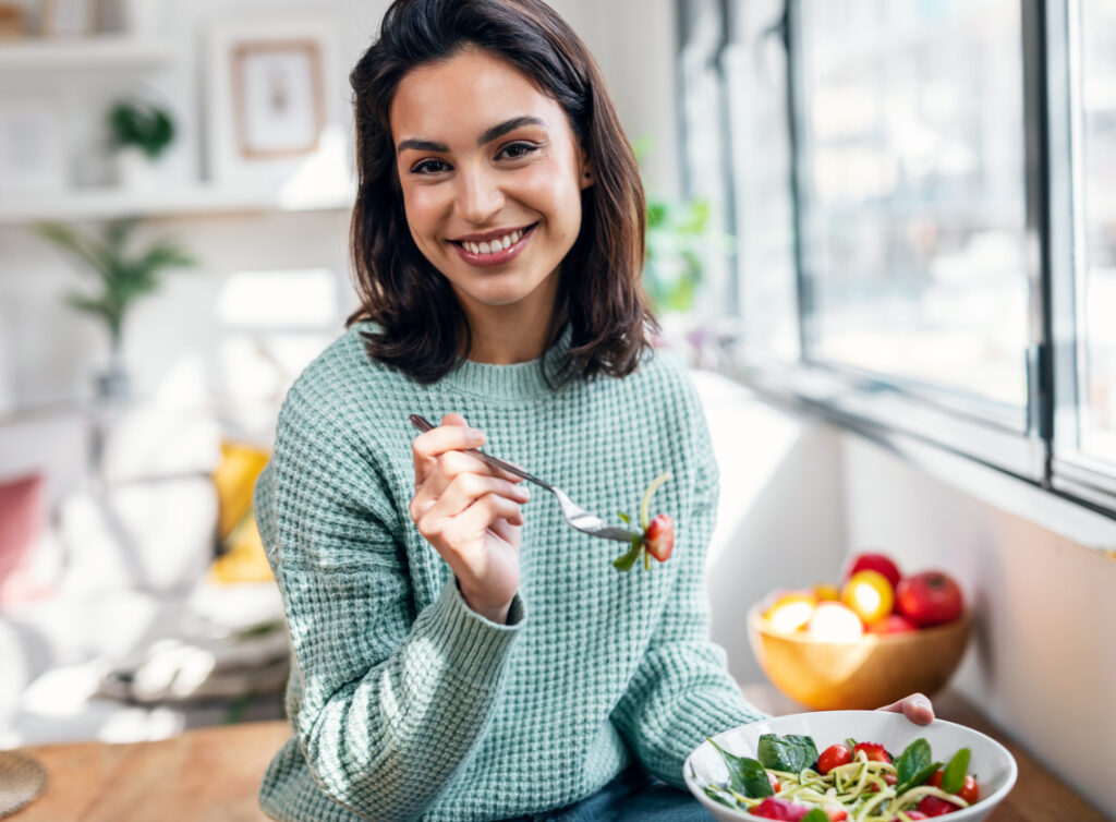 Woman eathing healthy salad made with fruits and vegetables