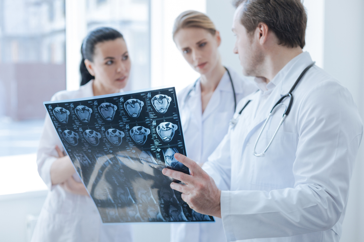 Concentrated radiographs working in a laboratory have a discussion while holding computed tomography photo.