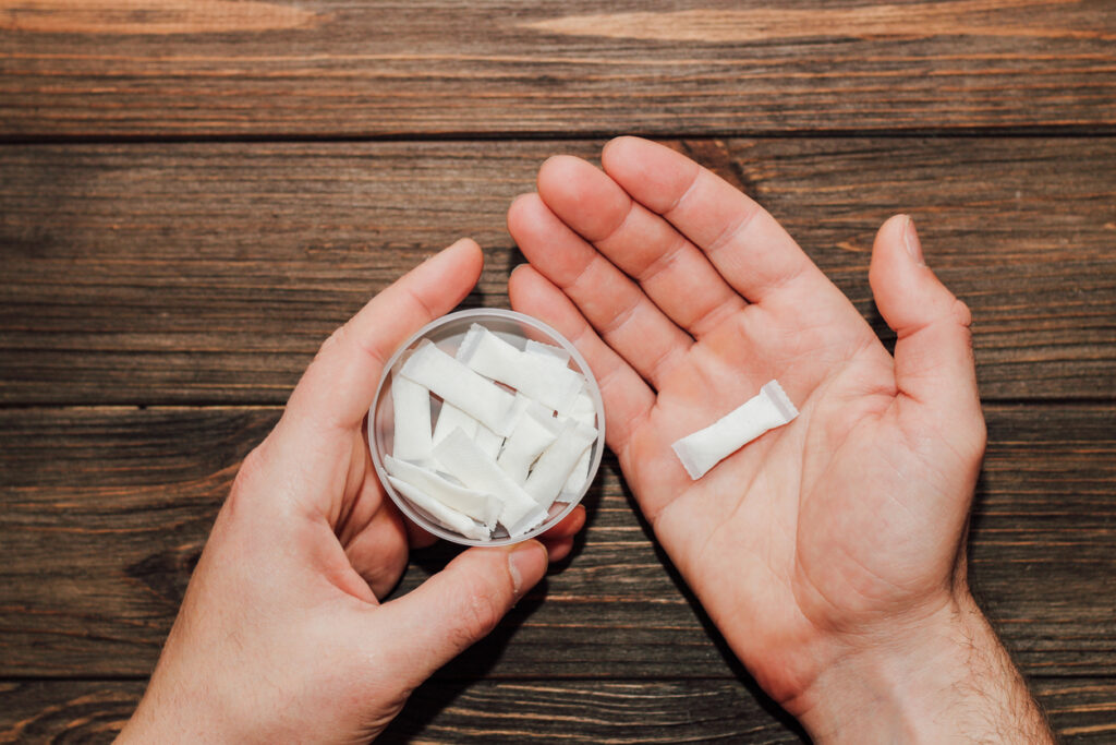 Hands holding box of nicotine pouches and single pouch