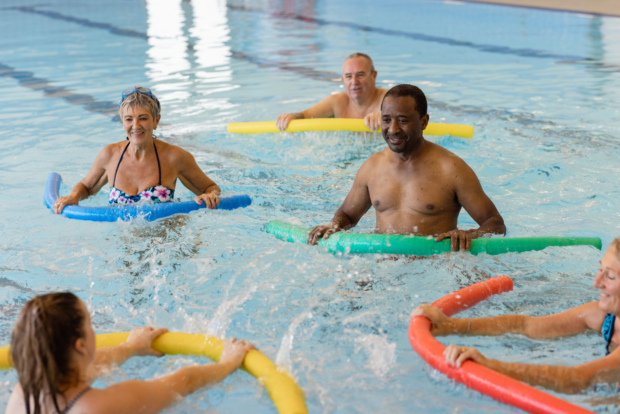 A swimming instructor teaching an aqua fitness using pool noodle floats.