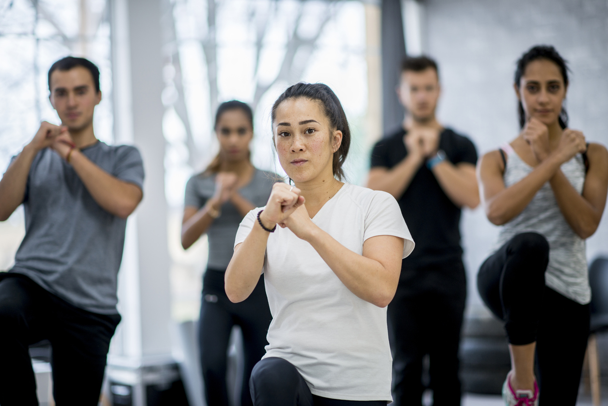 A group of men and women take a defensive pose in a non-contact boxing class.
