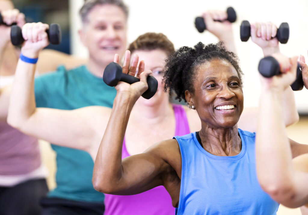 Senior African-American woman in exercise smiling while lifting hand weights. Purpose and drive can make workouts more enjoyable and help you accomplish your fitness resolutions.