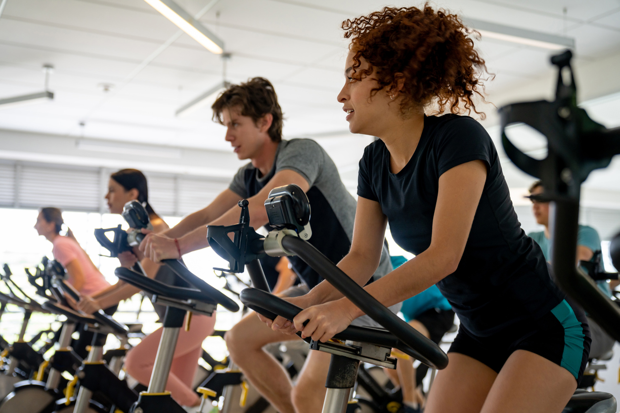 A group of people work out in an indoor cycling class.