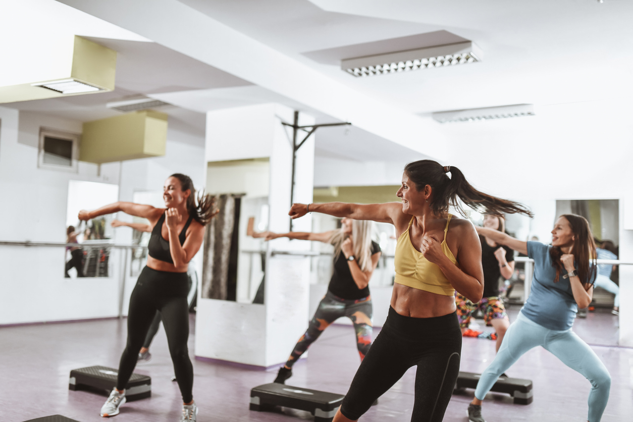 A group of female athletes practice moves during a kickboxing fitness at the gym.