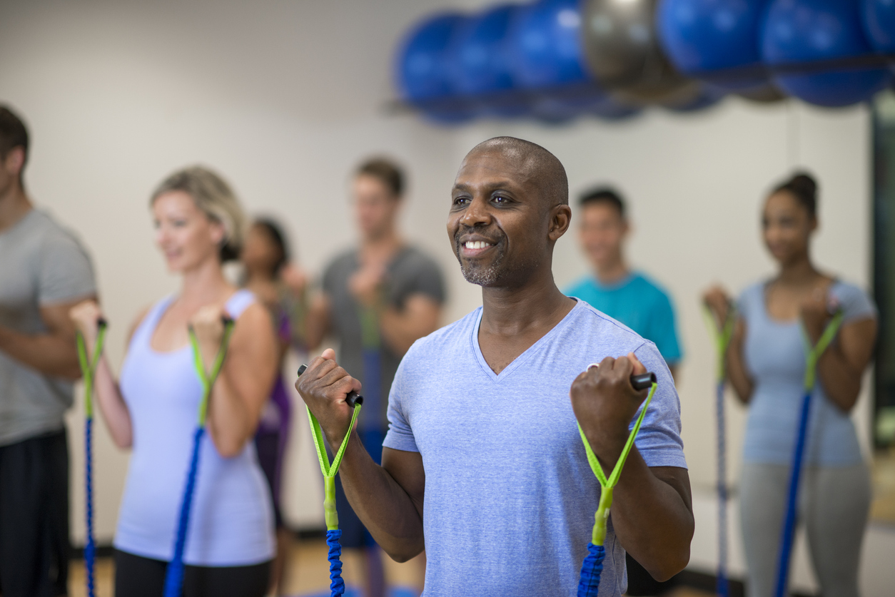 A group of adults do bicep curls during a fitness at the gym.