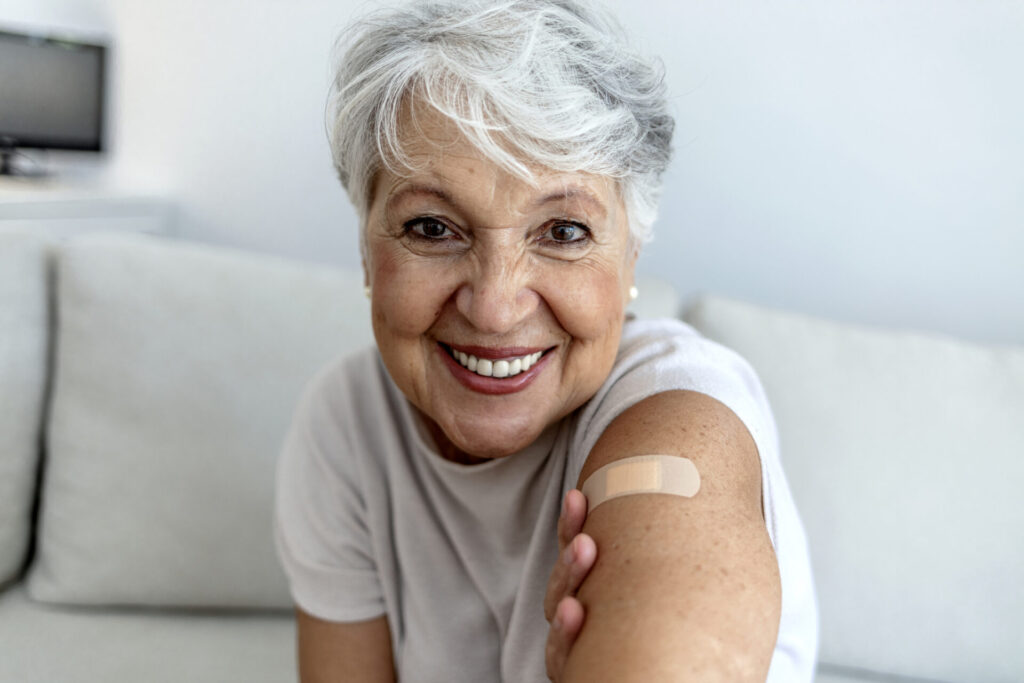 Smiling woman with bandaid on upper arm. Vaccines are recommended for prevention of severe RSV in adults.