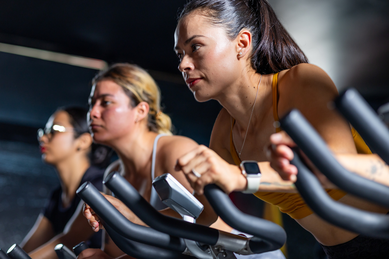 A woman focuses while pedaling in an indoor cycling class.