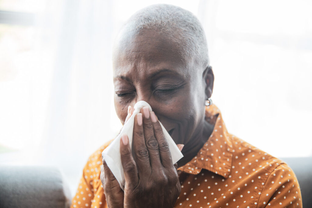 Woman with sniffles using tissue. RSV in adults often exhibits mild cold-like symptoms.