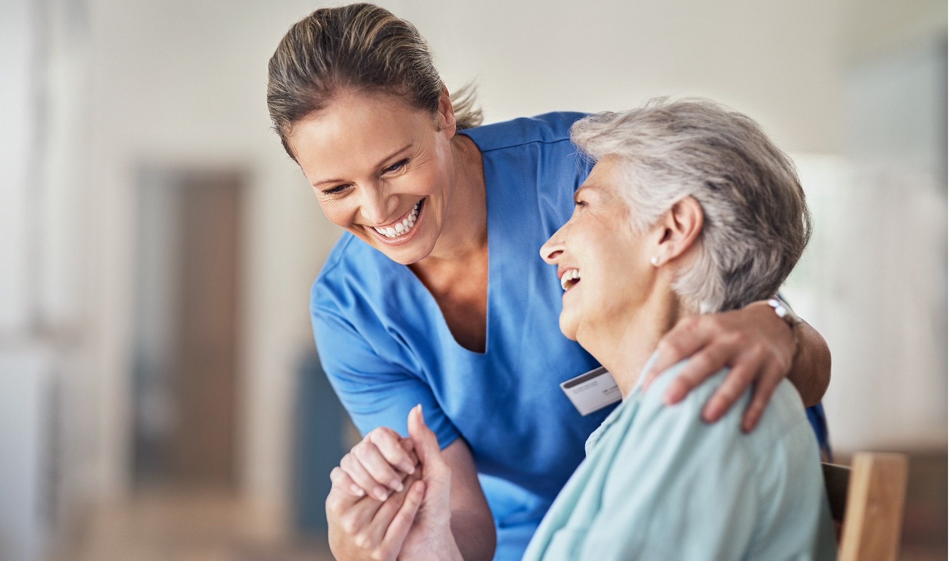 Shot of a young caregiver caring for her elderly patient in her home